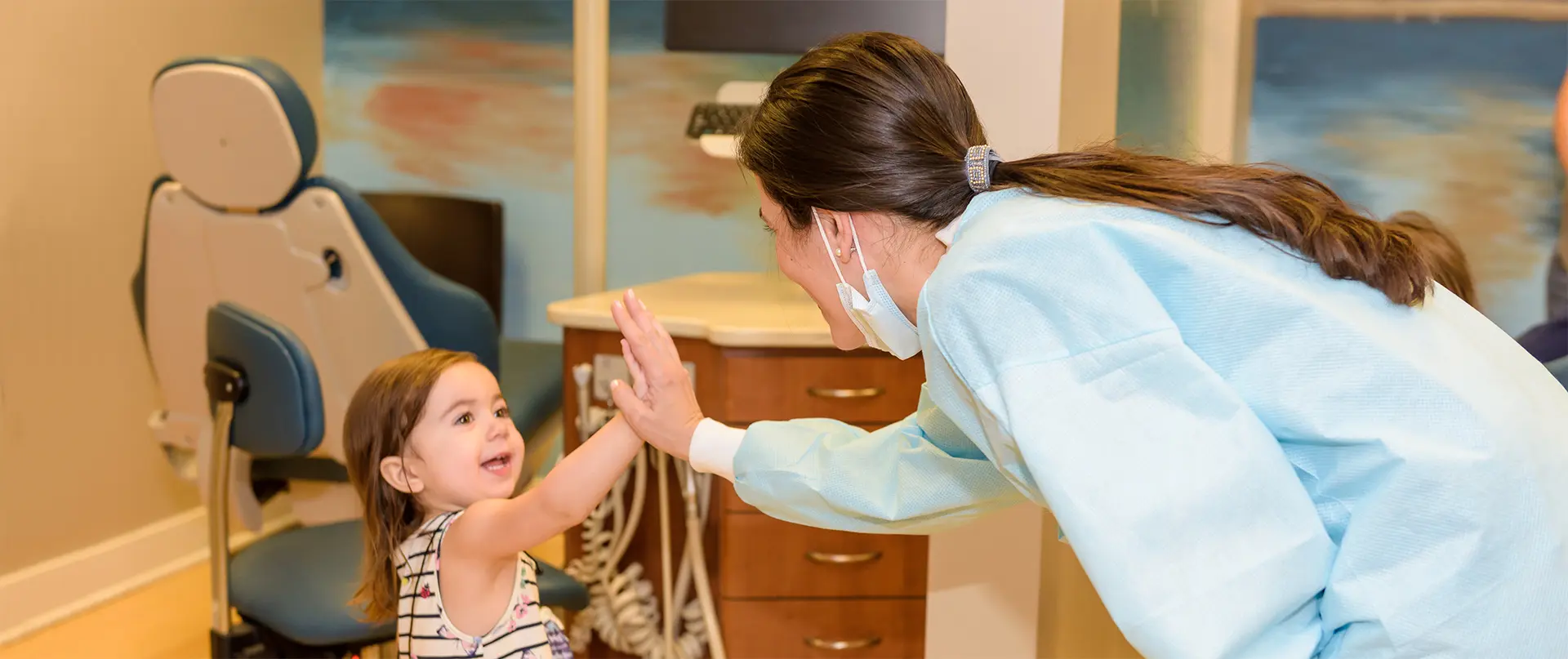 At Star Smiles Pediatric Dentistry in Bloomingdale or Naperville, IL, a pediatric dentist in scrubs high-fives a young girl beside a dental chair.