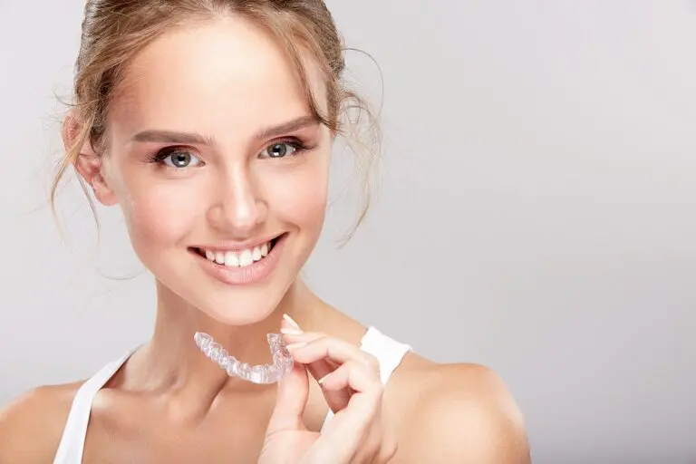 a blond woman holding invisalign after understanding invisalign cost in Bloomingdale and Naperville, IL