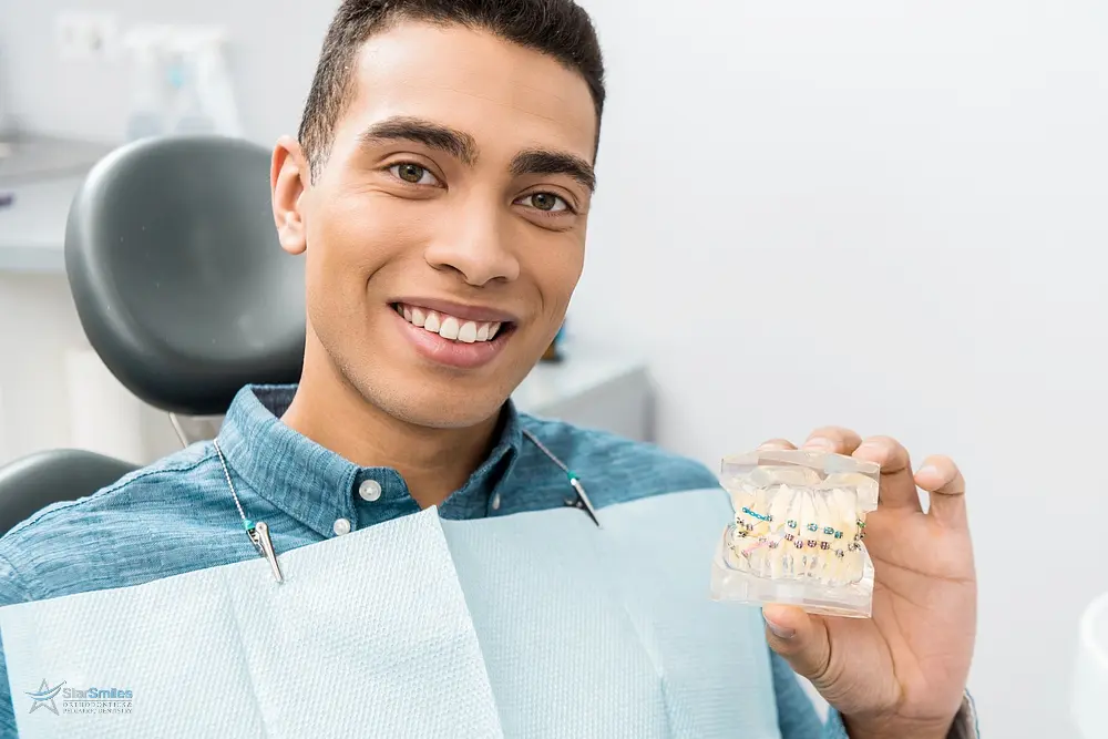 Smiling patient holding a dental model with clear aligners, showcasing how to fix overbite in Bloomingdale and Naperville, IL discreetly.