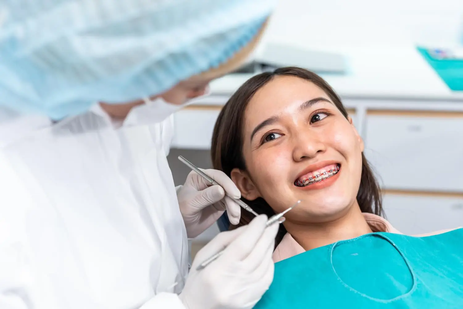 At Star Smile Orthodontics in Bloomingdale IL, a dentist uses dental tools to examine a smiling patient with braces in the clinic.