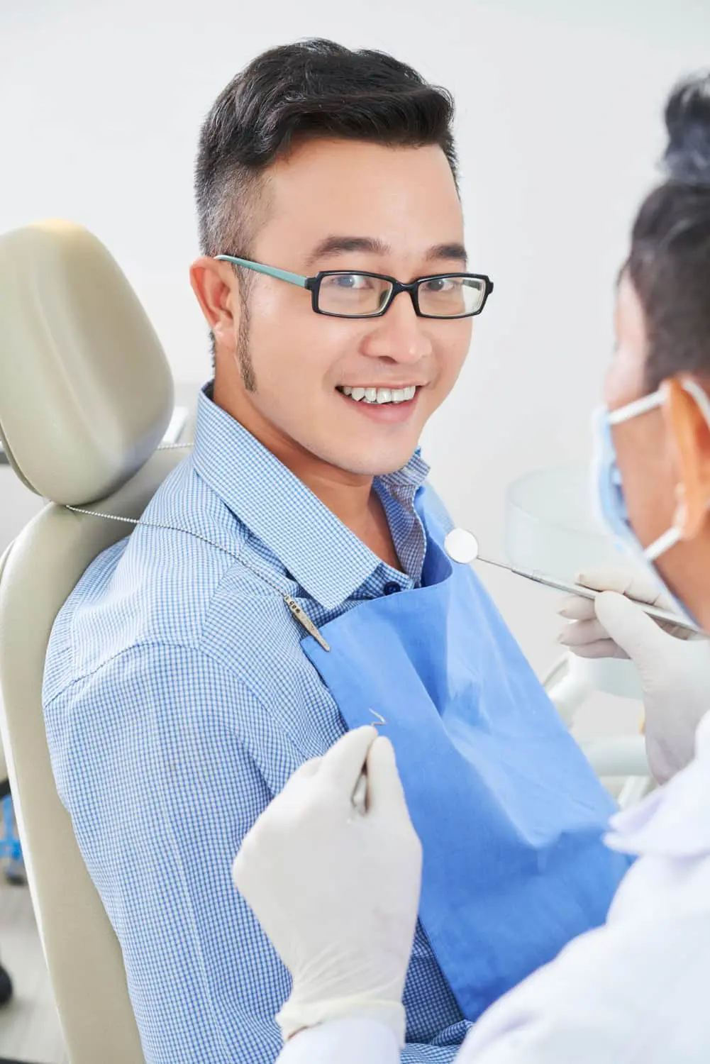 A man sits in a dental chair smiling as a dentist with gloves and a mask holds instruments near his mouth at Star Smile Orthodontics in Bloomingdale, IL.