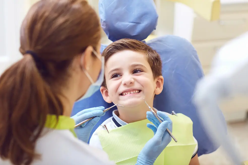 A boy child patient with open mouth examining by dentist with orthodontic appliances modern in Naperville, IL.