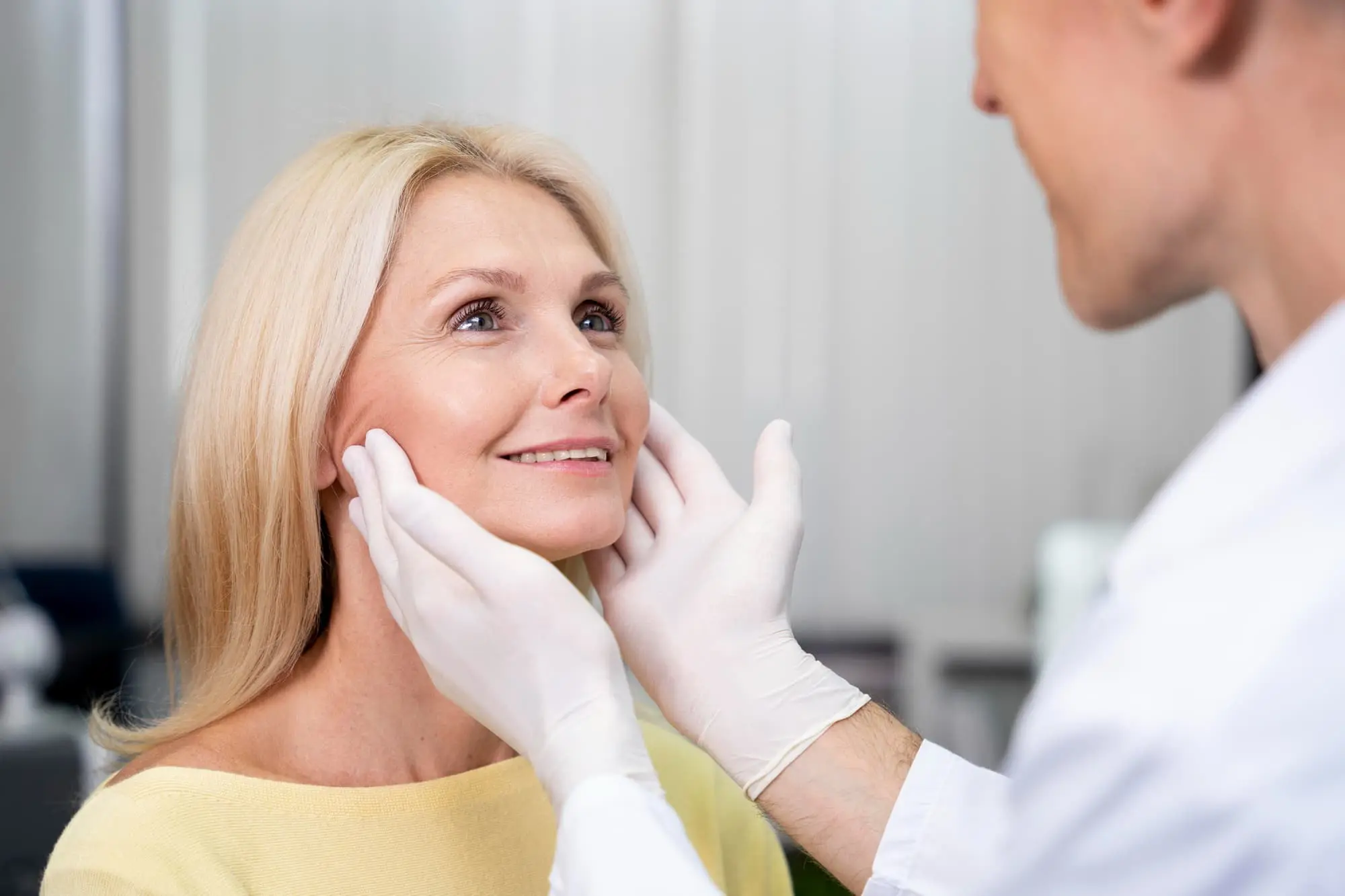 A dentist meticulously examines an older woman in a dental chair, focusing on his oral health with the possibility of recommending jaw surgery while wearing gloves in Bloomingdale and Naperville, IL.