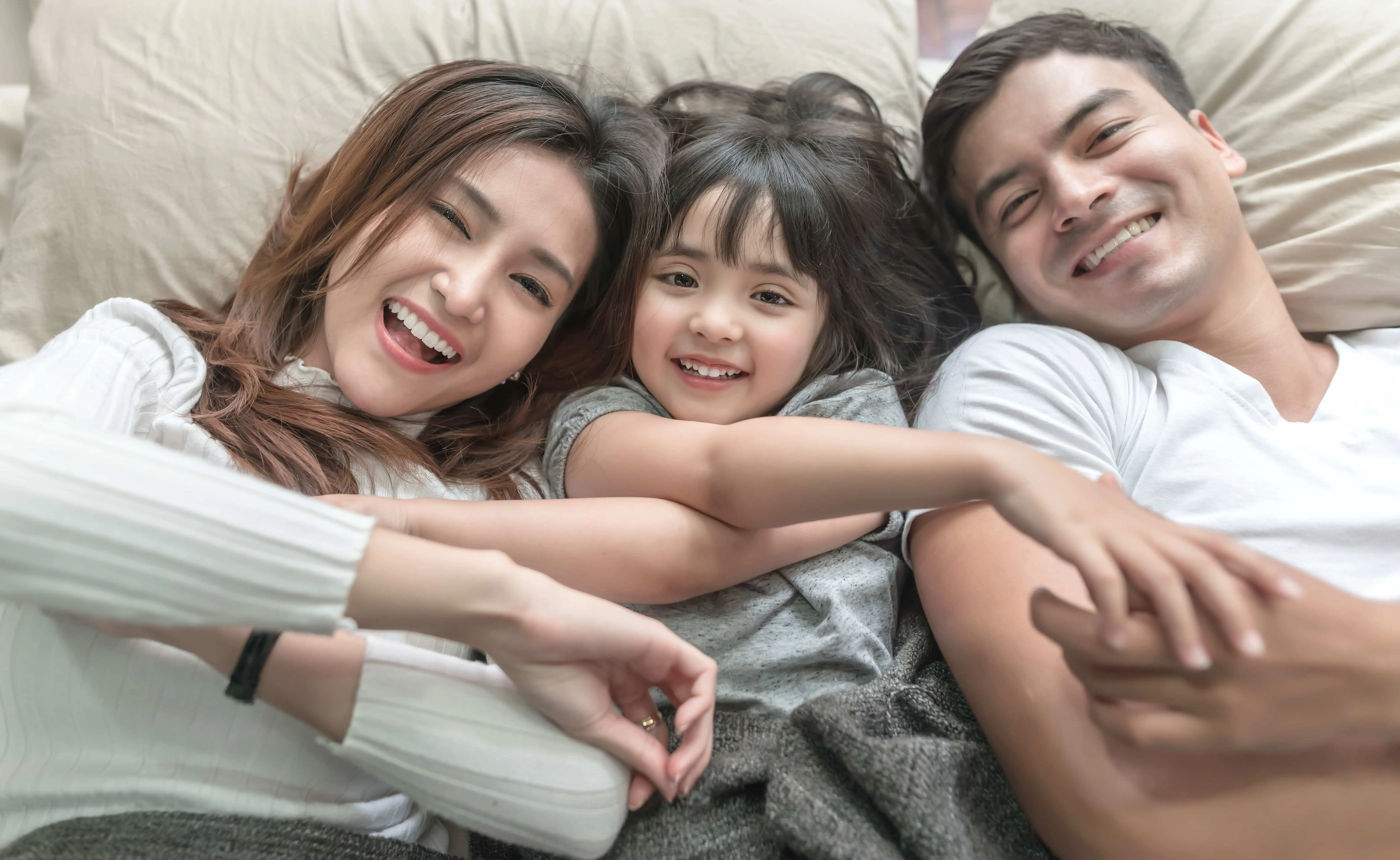 Close-up of smiling family lying on bed at home show health smile, cause orthodontic treatment at Star Smiles Orthodontics and Pediatric Dentistry with best orthodontic appliances in Naperville, IL