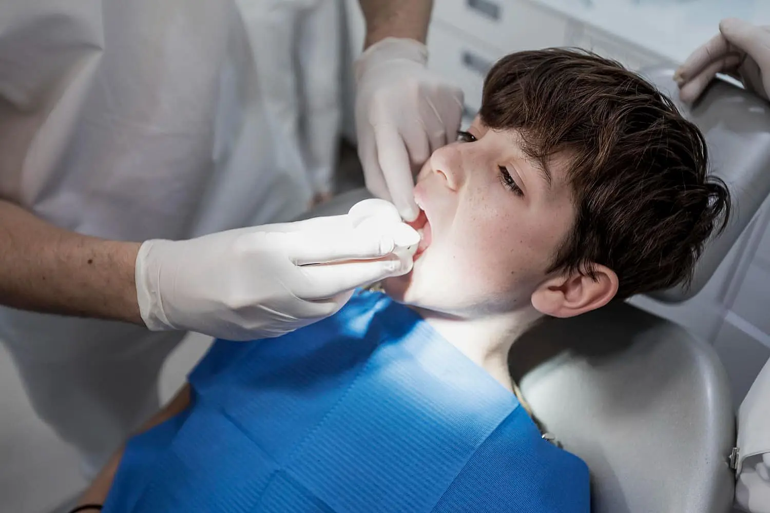 A children in a dental chair examined by a dentist using a dental tools for checkup tongue thrust from patient in Bloomingdale and Naperville, IL.
