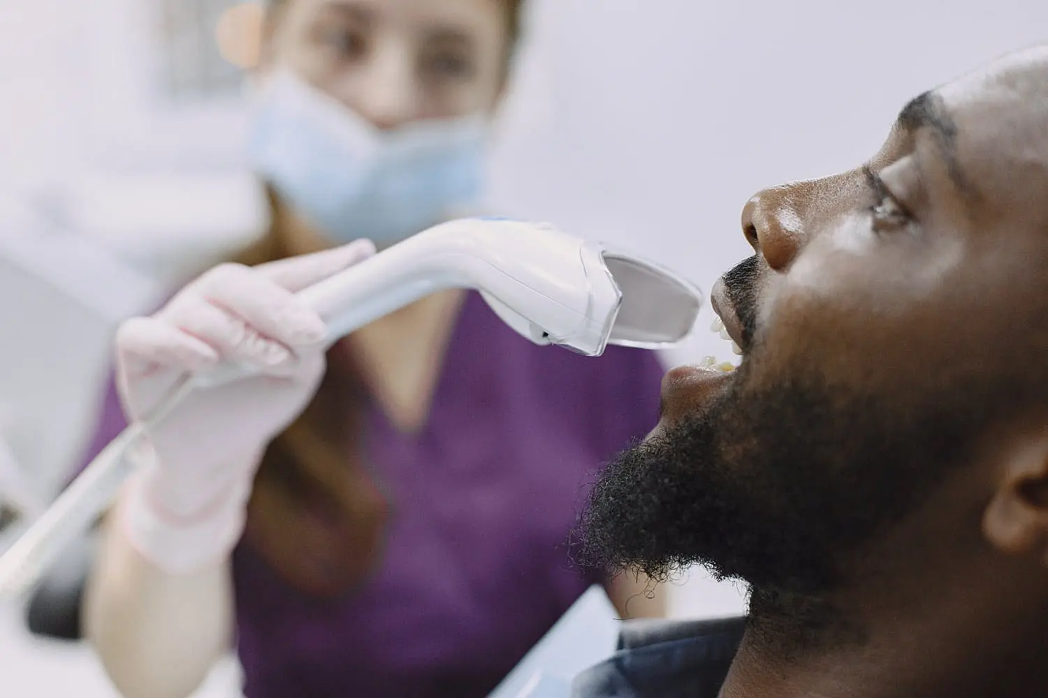 A dentist in a mask examines a mouth breather's teeth using a dental tool in the clinic. The patient is reclined comfortably in the dental chair in Bloomingdale and Naperville, IL.