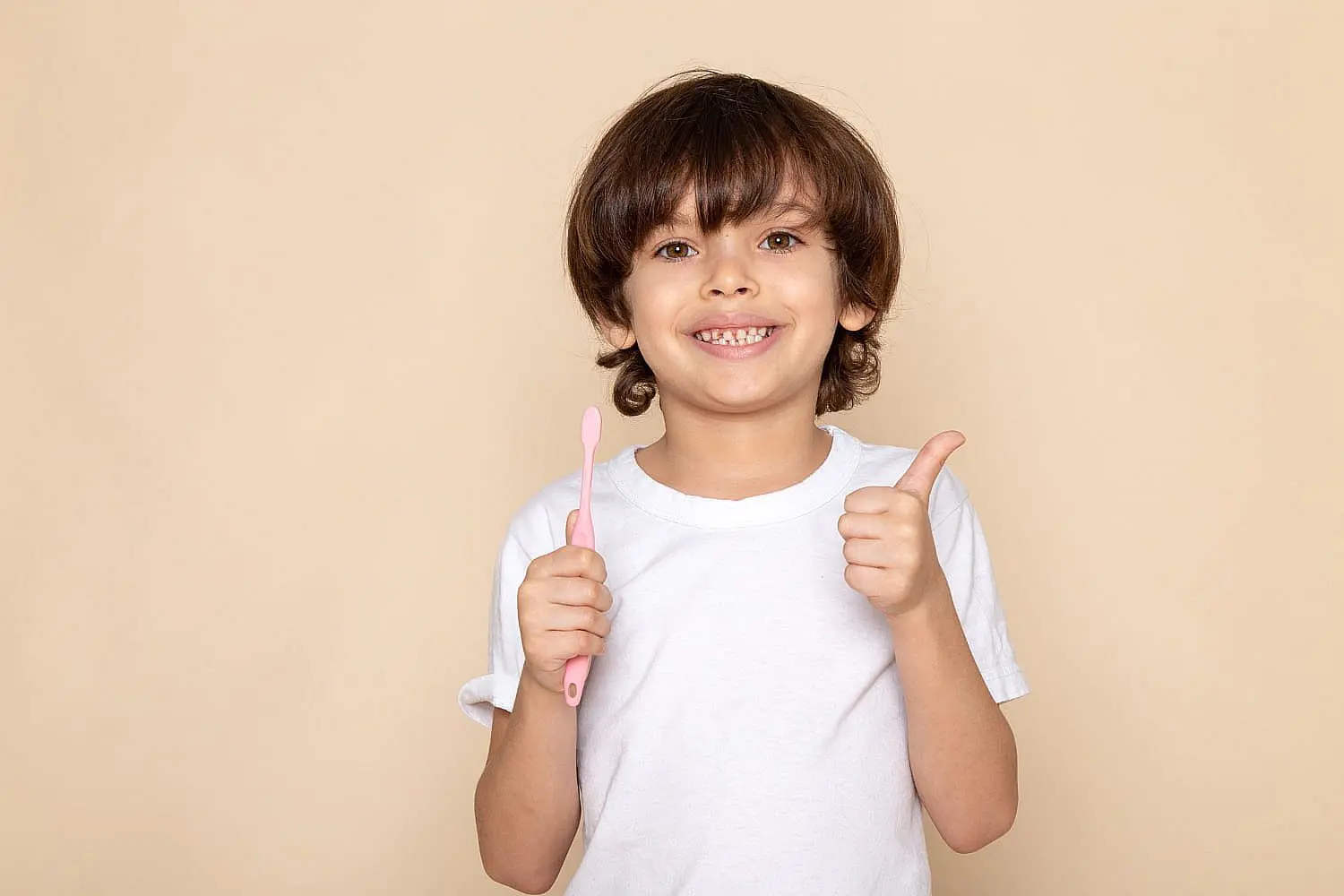 A smiling child gives a thumbs up and holds a pink toothbrush show common orthodontic issues with her teeth need children’s orthodontist for begin treatment dental in Bloomingdale and Naperville, IL.