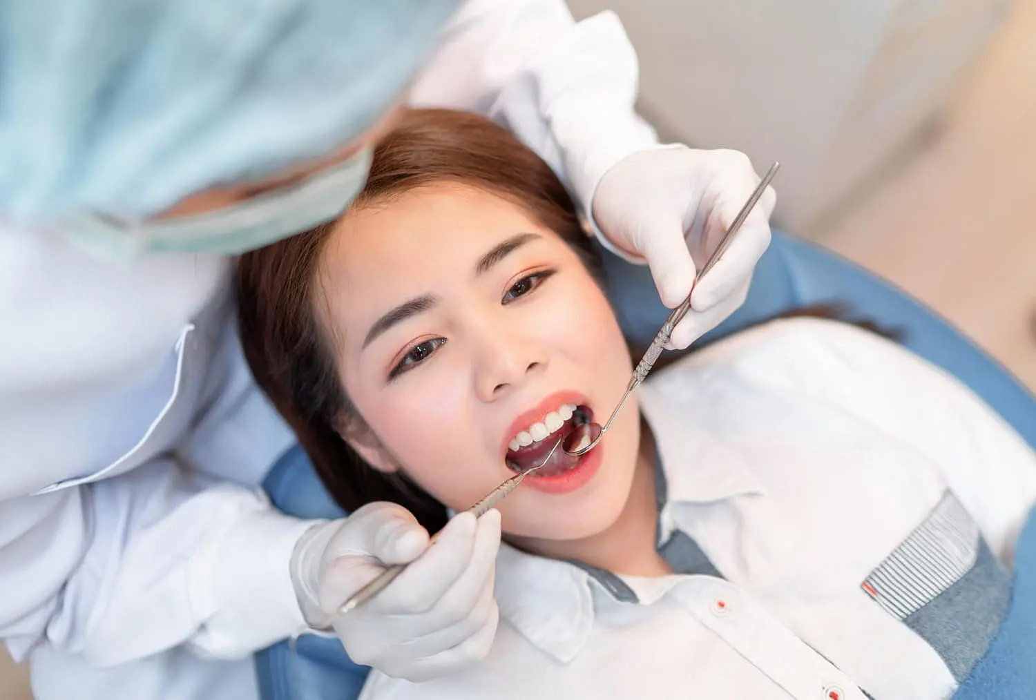 A woman is having a dental checkup at Star Smiles Orthodontics and Pediatric Dentistry in Naperville, IL. A dentist holds a mirror for help patient begin use metal braces for her dental treatment.