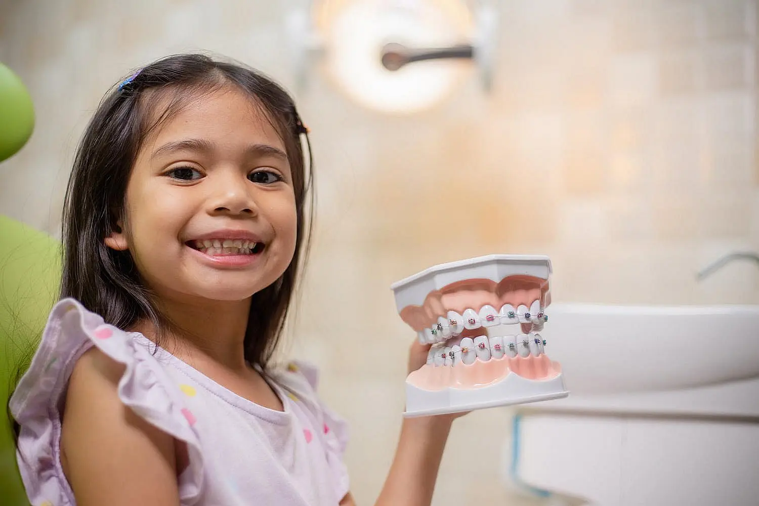 A child sits in a dental chair, smiling beneath the bright dental light, proudly showing getting affordable braces in Bloomingdale or Naperville, IL.