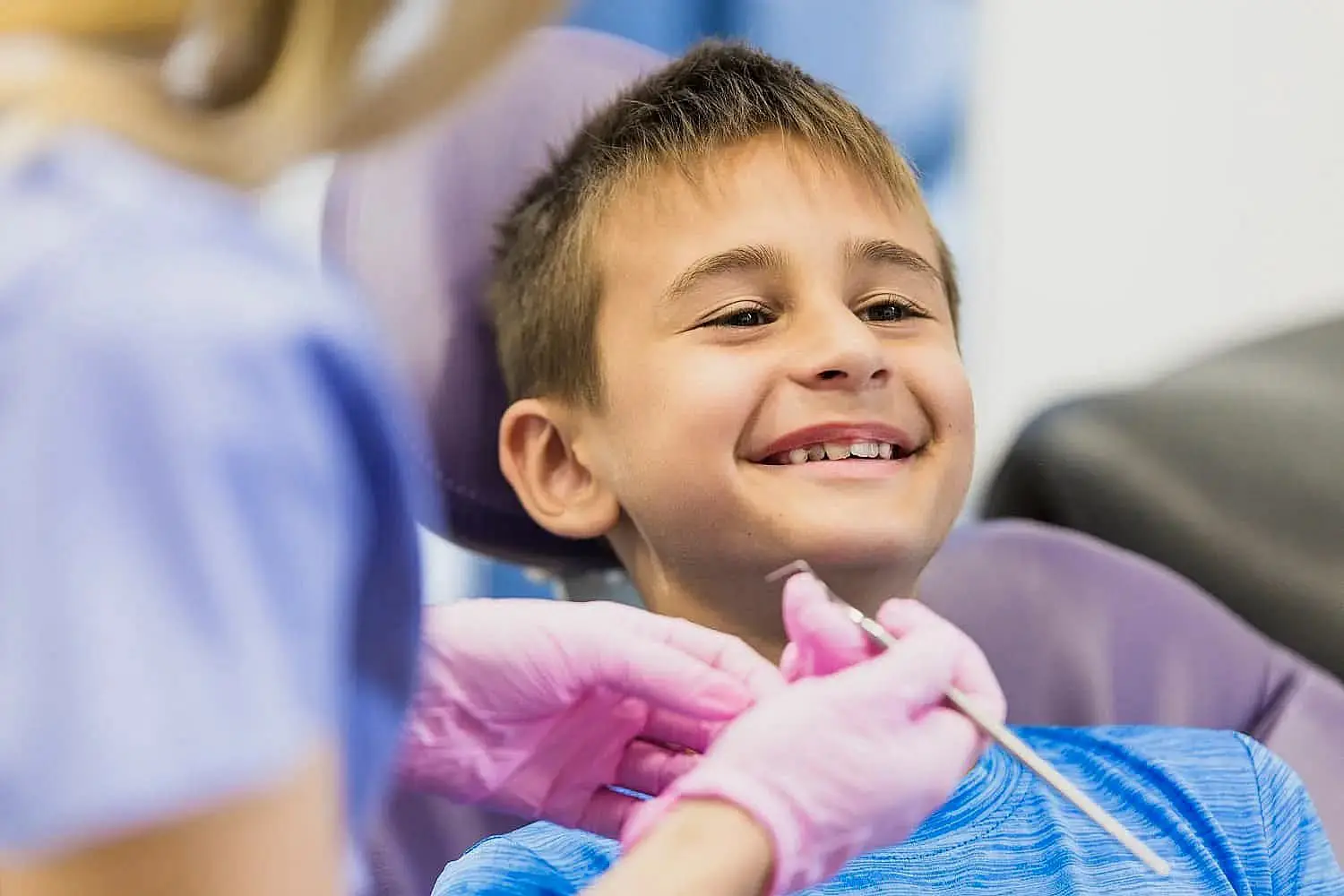 A child sits in a dental chair while a children’s orthodontist, wearing gloves, cleans their teeth with a dental tool in Bloomingdale and Naperville, IL.