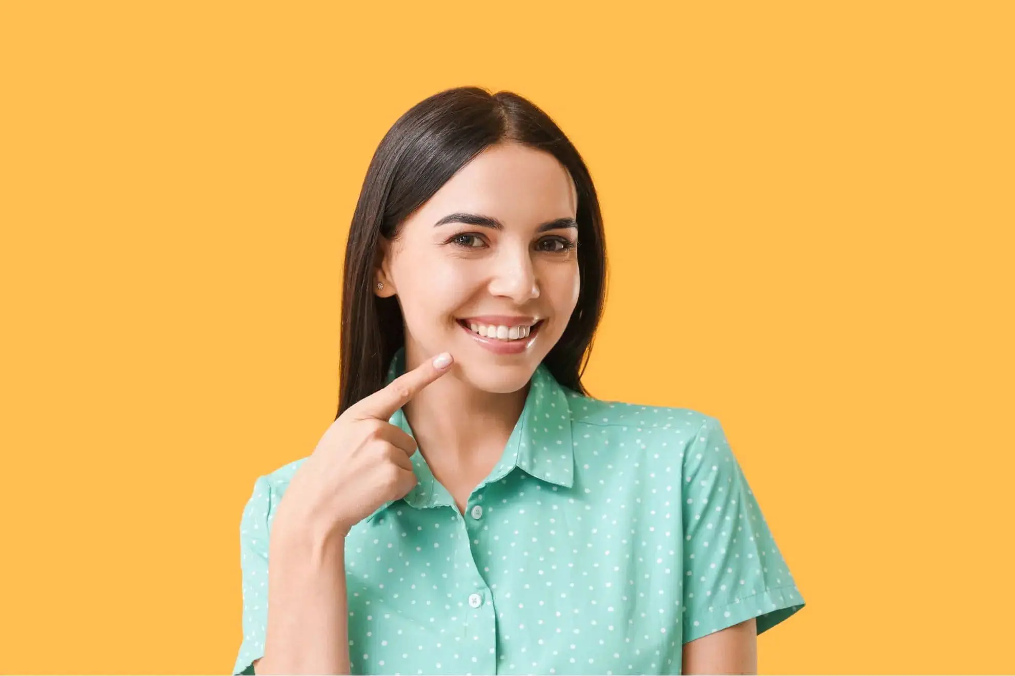 A woman show beautiful smiles confidently and points to her straight teeth, the result of Invisalign treatment covered by insurance at Star Smiles Orthodontics and Pediatric Dentistry in Bloomingdale and Naperville, IL.