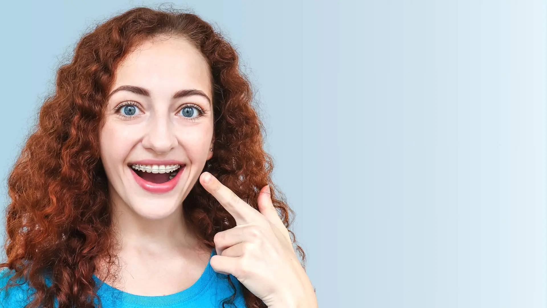 A woman with curly hair wearing ceramic braces smiles, highlighting a popular treatment offered by Star Smiles Orthodontics and Pediatric Dentistry in Bloomingdale and Naperville, IL.