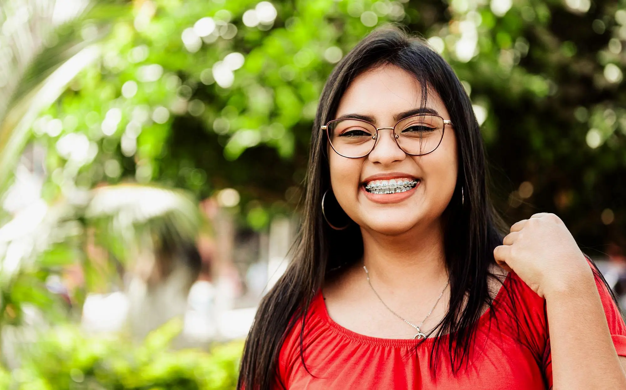 A young woman with braces smiles, highlighting the importance of oral care for patients with braces and getting free orthodontic consultation in Naperville, IL.