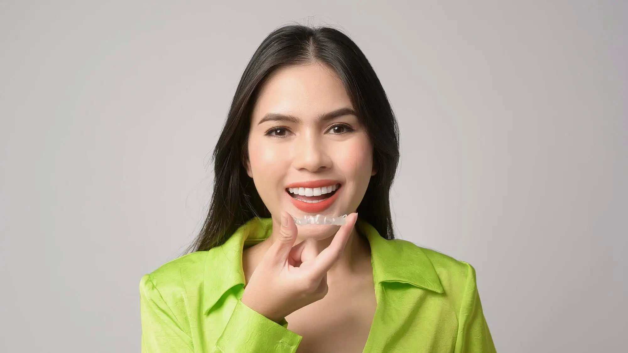Woman holding a clear dental aligner, feel Invisalign insurance at Star Smiles Orthodontics and Pediatric Dentistry in Bloomingdale and Naperville, IL.