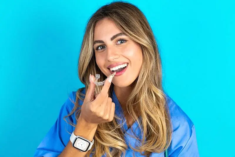 Woman smiling and holding a clear dental aligners from Invisalign at Star Smiles Orthodontics and Pediatric Dentistry in Bloomingdale and Naperville, IL.