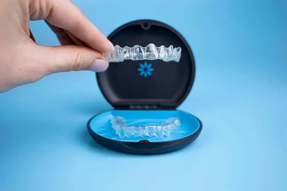 A person hold a clear dental aligners from case box Invisalign in Bloomingdale, IL.