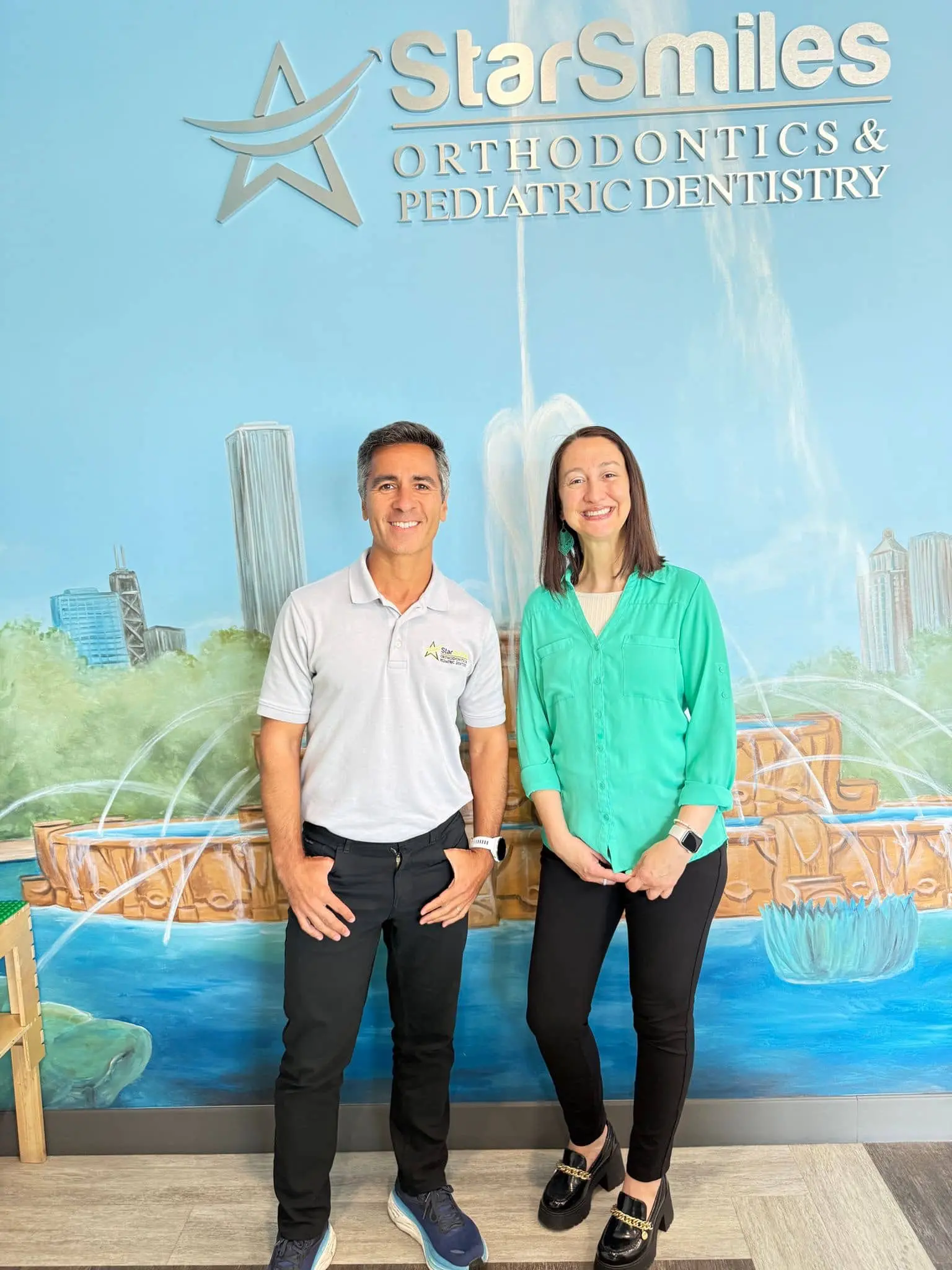 Dr. Andre Jam & Dr. Sara Spector smile before a mural and Star Smiles Pediatric Dentistry sign in Bloomingdale or Naperville, IL.
