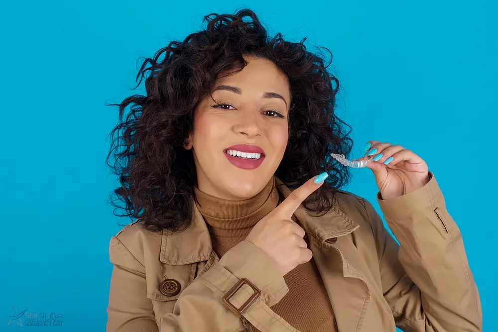 pregnant woman holding invisalign clear aligners pointing dental healthcare confidence concept - Aligners vs Braces in Bloomingdale and Naperville, IL