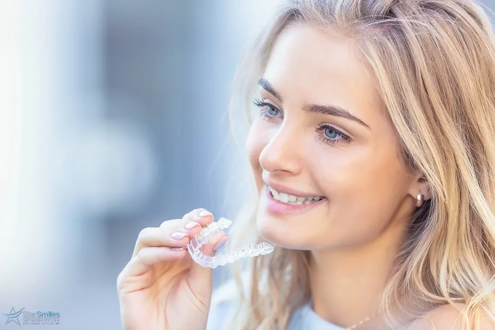 young attractive woman holding invisalign clear aligners - How Long Does Invisalign Take in Bloomingdale, IL