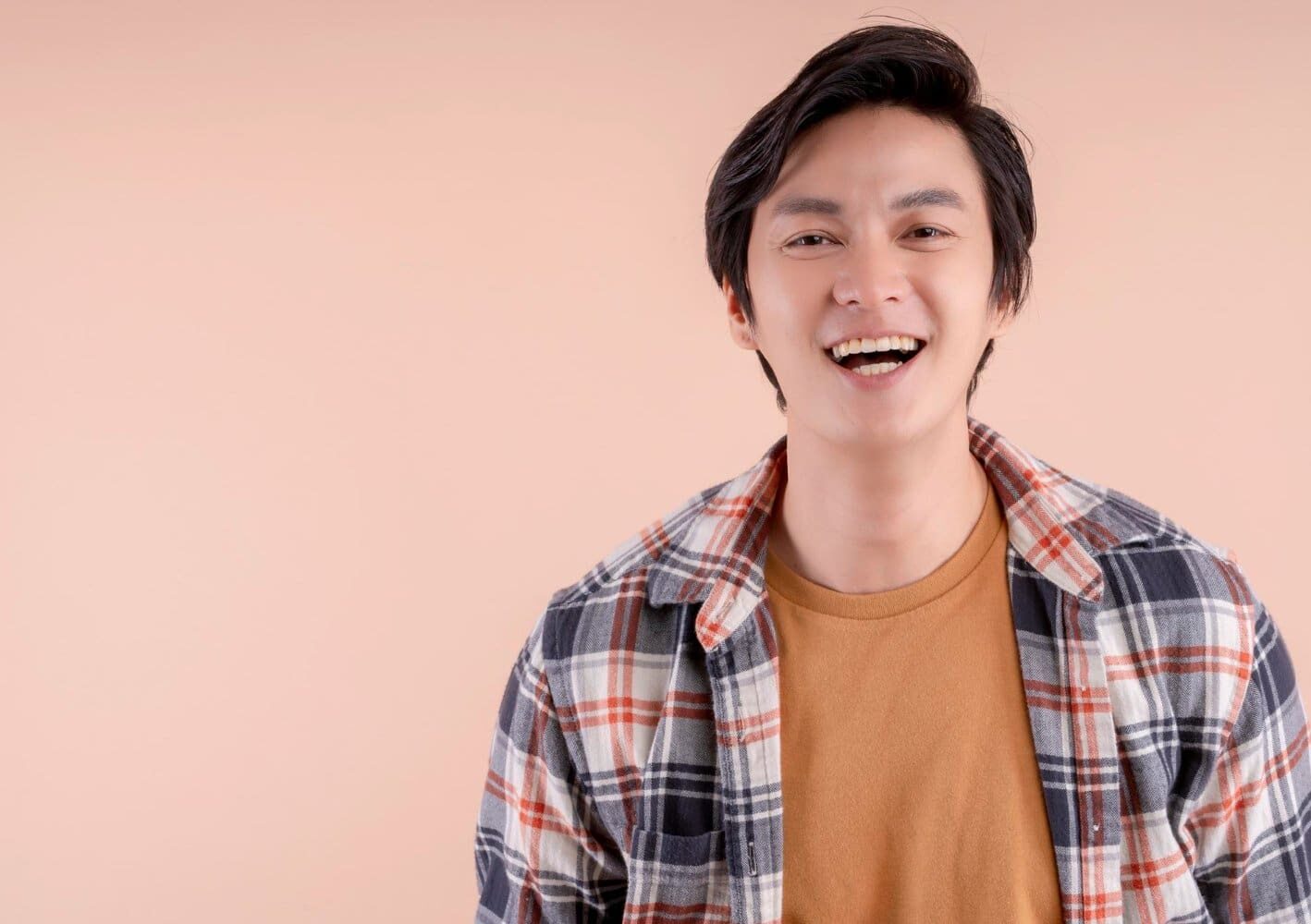 A man with dark hair, wearing a brown clothes, smiles at the camera, revealing the subtle outline of a Palatal Expander in his teeth—an example of treatment available at Star Smiles Orthodontics and Pediatric Dentistry in Bloomingdale and Naperville, IL.