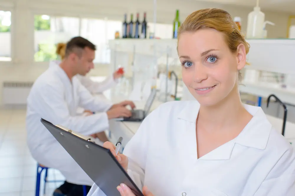 At Star Smiles Orthodontics and Pediatric Dentistry, a woman in a white lab coat holds a clipboard and pen while reviewing plan limitations for orthodontic insurance plans, with another person working in the background. This scene takes place in Bloomingdale and Naperville, IL.
